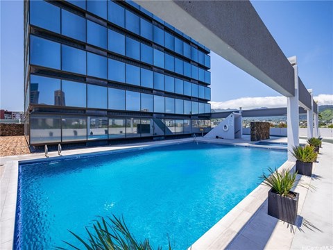 A swimming pool in front of a modern building with a glass facade.