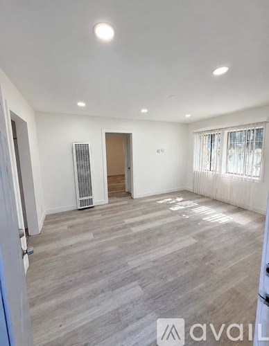 A spacious room with wooden flooring and white walls.