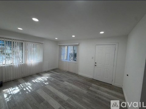 A room with a wooden floor and a window with blinds.