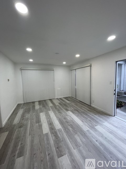 A room with wooden flooring and white walls.