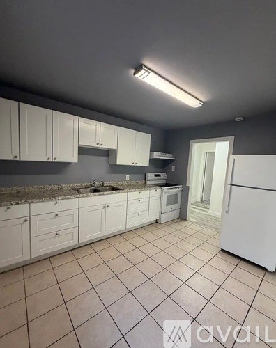 A kitchen with white cabinets and a white refrigerator.