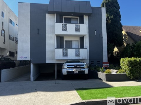 A black and white building with a car parked in front.