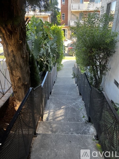 A narrow alley with a metal fence on the side and steps leading up.
