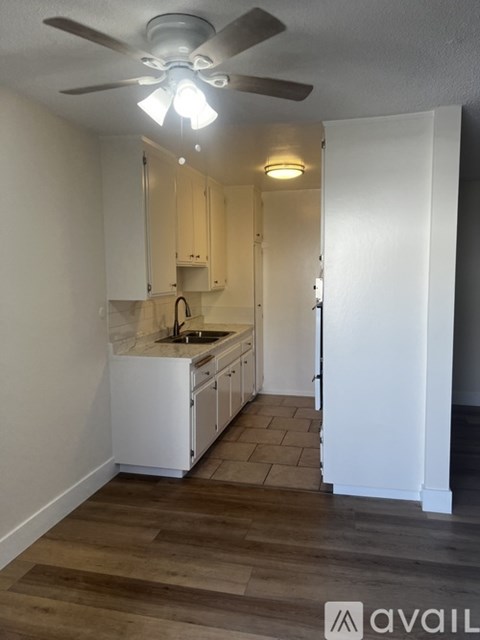 A kitchen with white cabinets and a wooden floor.