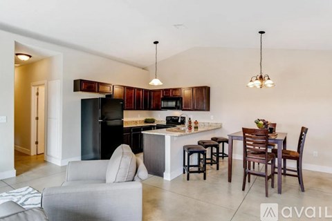 A kitchen with a black refrigerator and wooden cabinets.