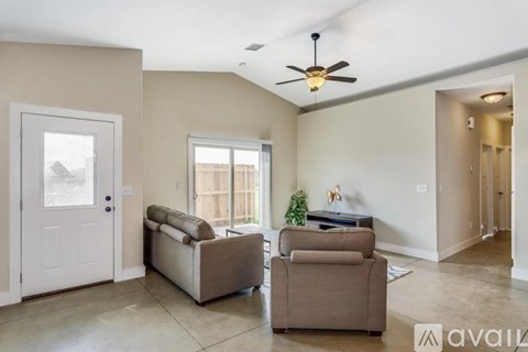 A living room with a sofa, armchair, and a ceiling fan.