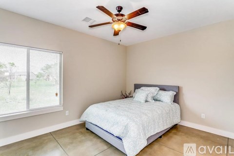 A bedroom with a bed, a ceiling fan, and a window.