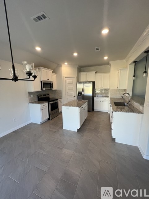 A kitchen with white cabinets and a grey floor.