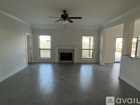 A spacious living room with a fireplace and a ceiling fan.