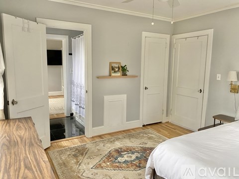 A bedroom with a bed, two doors, and a rug.