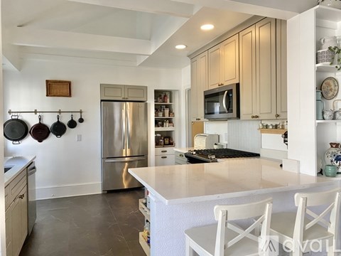 A kitchen with a white counter top and white chairs.