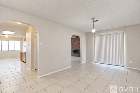 A spacious living room with a brick fireplace and a large arched doorway.