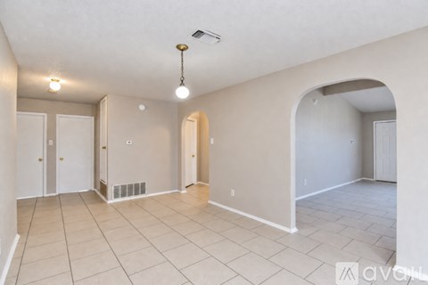 A spacious room with beige walls and a tiled floor.