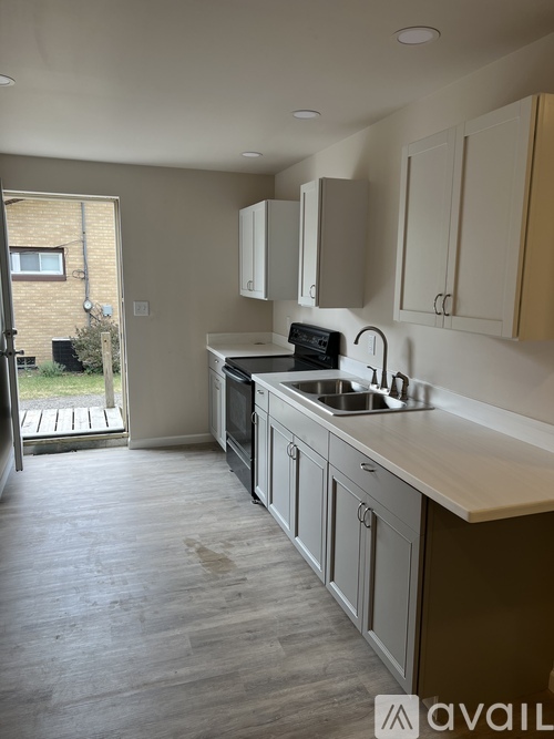 A kitchen with a sink, stove, and cabinets.