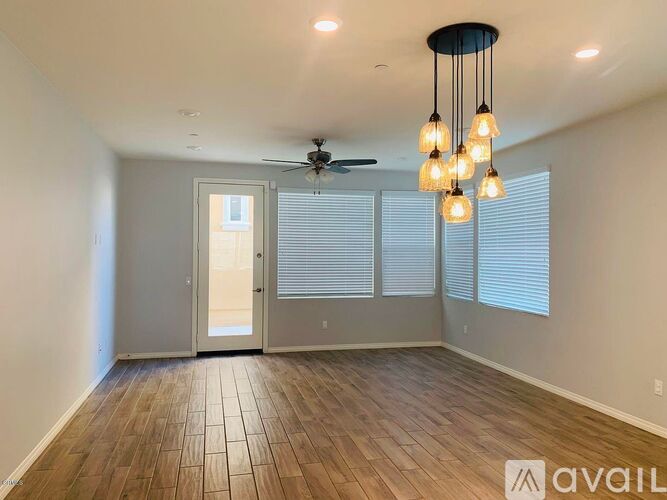 A room with wooden flooring and a ceiling fan with lights.