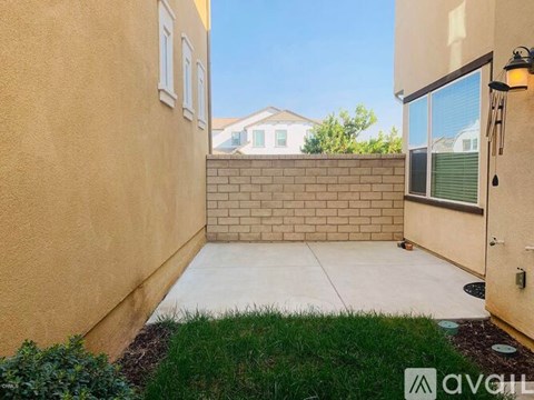 A backyard with a concrete patio and a brick wall.