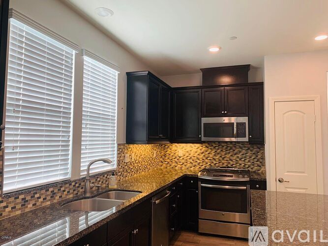 A kitchen with black cabinets and a tiled backsplash.
