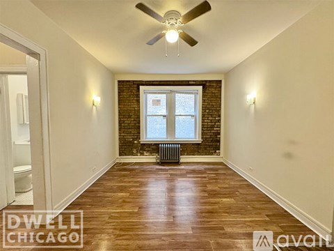 A room with a ceiling fan and a window with a radiator beneath it.