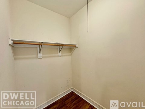 A white wall with a wooden shelf and a black pipe.