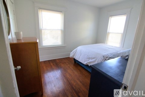 A bedroom with a bed, wooden floor, and a dresser.