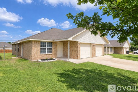 A house with a brown brick exterior and a white garage door is for sale.