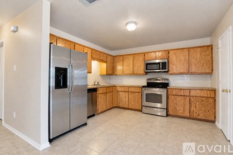 A kitchen with wooden cabinets and a stainless steel refrigerator.