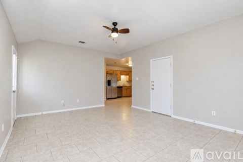 A spacious room with a ceiling fan and tiled flooring.