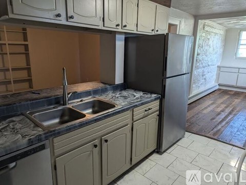 A kitchen with a sink, dishwasher, and refrigerator.