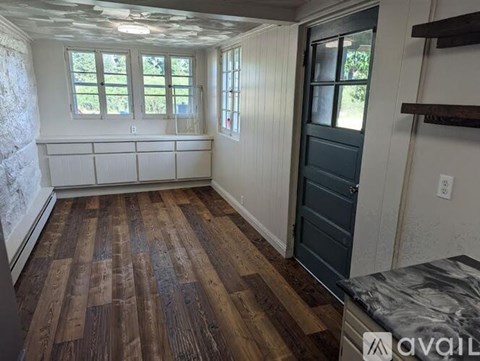 A room with wooden flooring and a dark door.