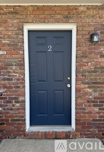 A dark blue door with a white frame and sidelights is set in a brick wall.