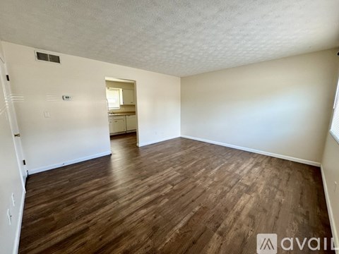 A room with wooden flooring and white walls is available for rent.