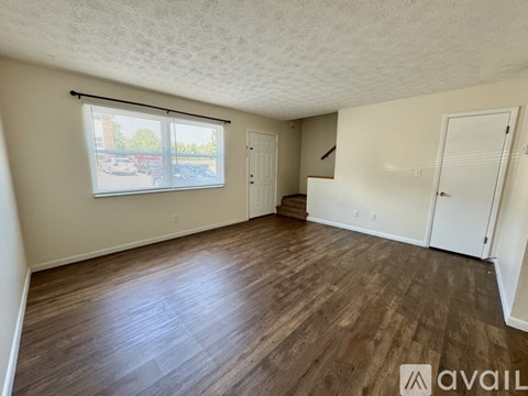 A room with wooden flooring and a window with blinds.