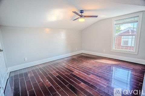 A room with a ceiling fan and a window showing a building outside.