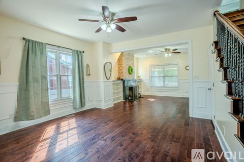A living room with wood floors and a ceiling fan.