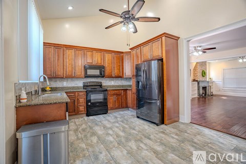 A kitchen with wooden cabinets and a black refrigerator.