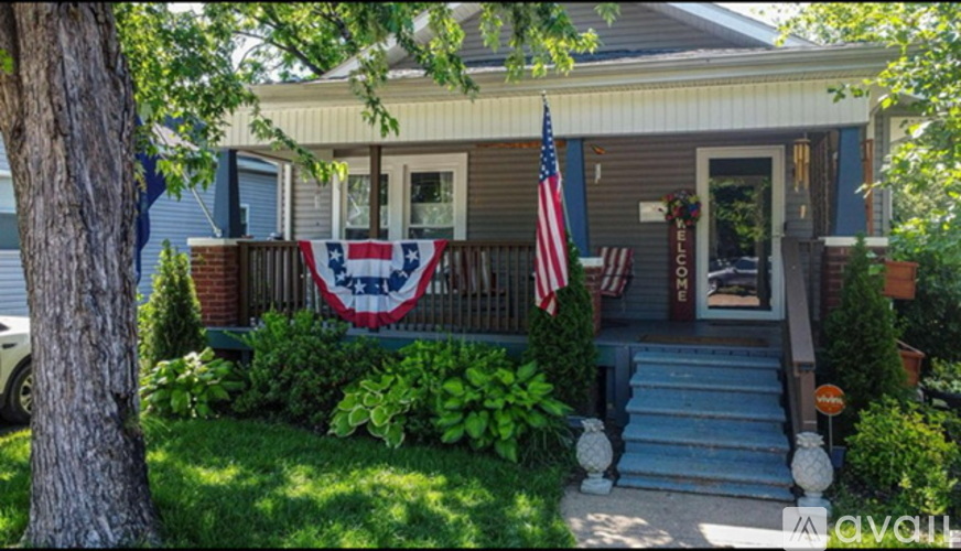 A house with a flag and a sign that says "For Sale".