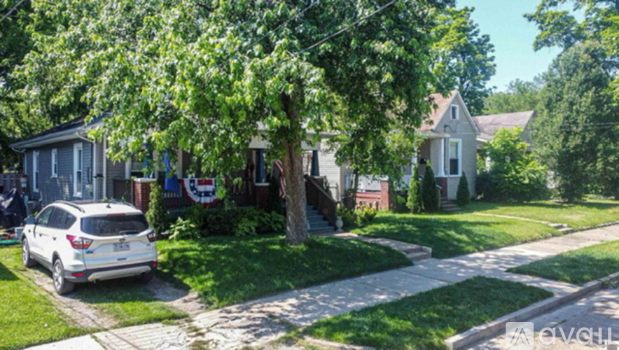 A white car is parked on a driveway in front of a house.