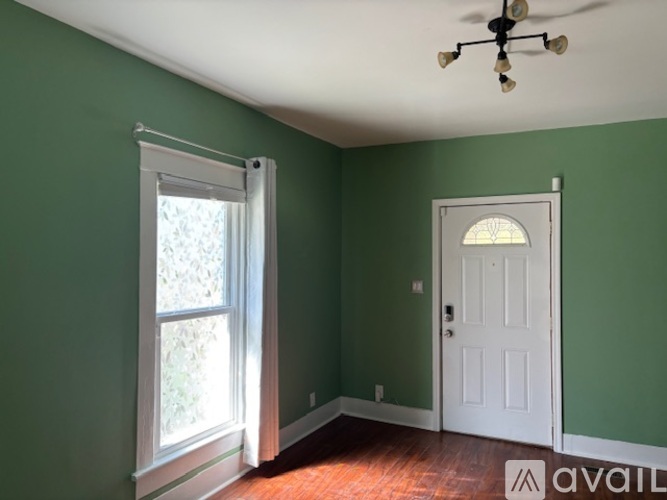 A room with green walls, a white door, and a window with white blinds.
