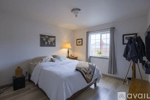 A bedroom with a large bed and a window with curtains.