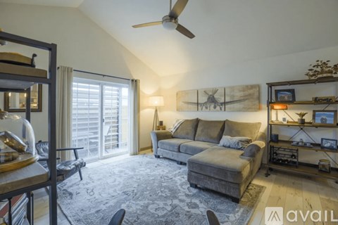 A living room with a grey sofa and a ceiling fan.