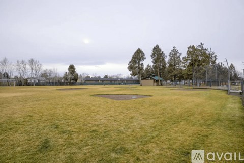 A baseball field with a fence and trees in the background.