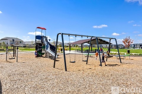 A playground with a slide and swings in a sunny day.