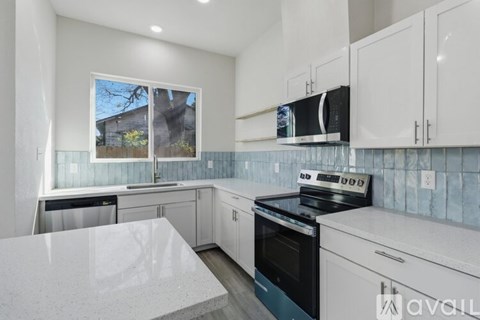 A kitchen with white cabinets and a marble countertop.
