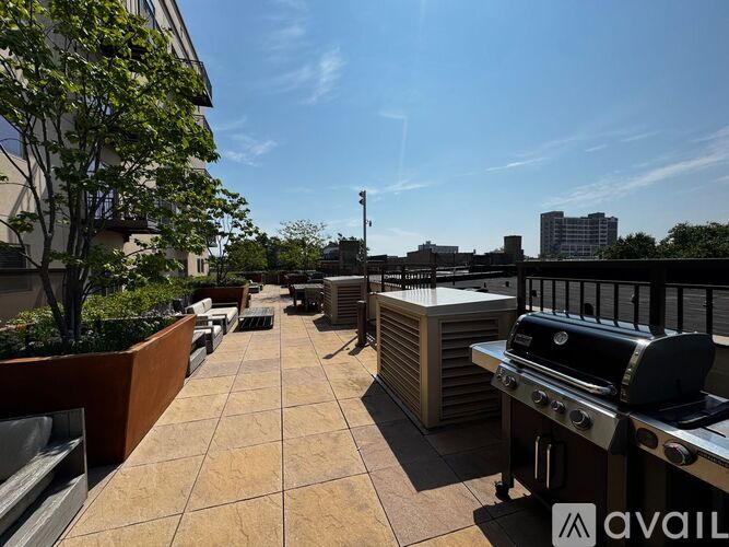 A patio with a grill and a table is on the roof of a building.