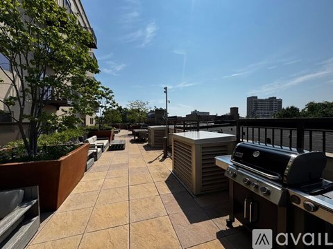A patio with a grill and a table is on the roof of a building.