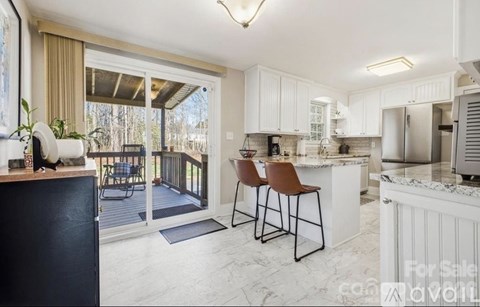 A kitchen with white cabinets and a black island is for sale.