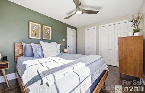 A bedroom with a large bed and a ceiling fan.