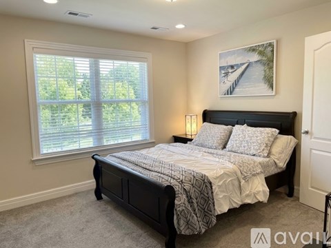A bedroom with a large bed and a painting on the wall.
