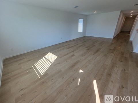 A room with wooden flooring and a window letting in sunlight.