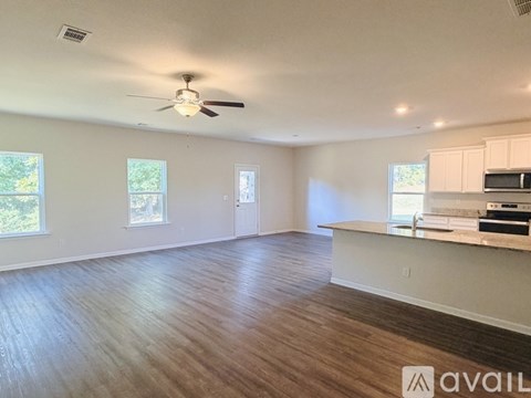 A spacious room with a ceiling fan and wooden flooring.